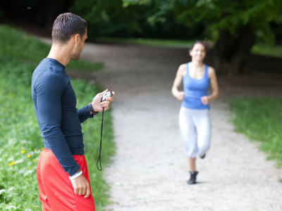 Personal trainer timing a female runner. Selective focus. Personal trainer timing a female runner. Selective focus.